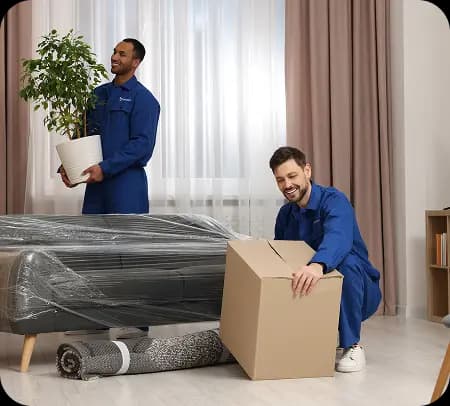 Professional movers in blue caps and uniforms loading and stacking cardboard boxes into moving truck